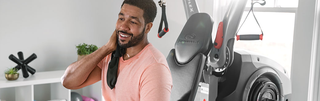 A man sitting on a BowFlex Revolution Home Gym.